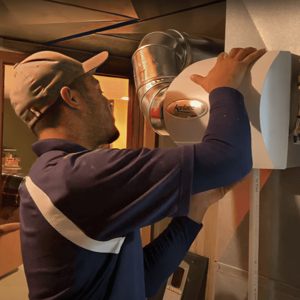 Logan Services HVAC technician installing humidifier to furnace.