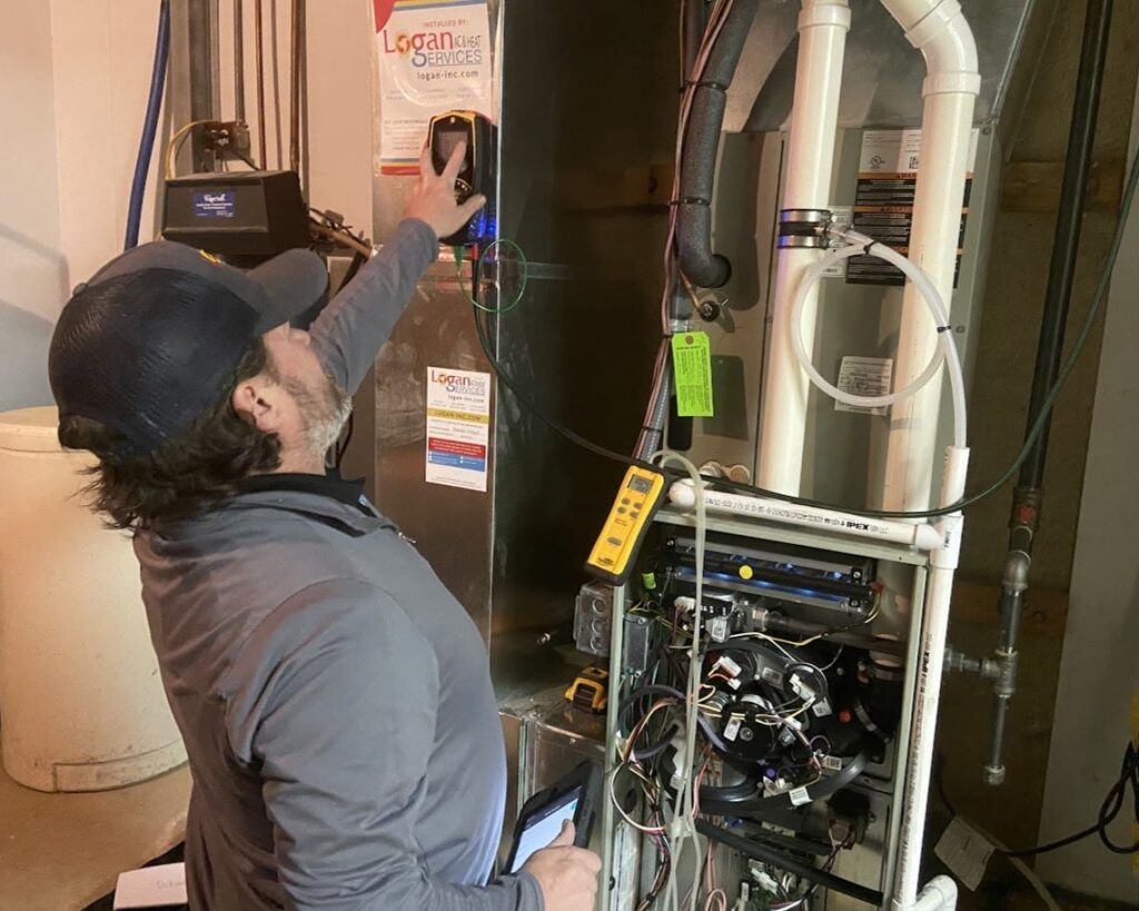 Logan Services HVAC technician performing furnace maintenance.