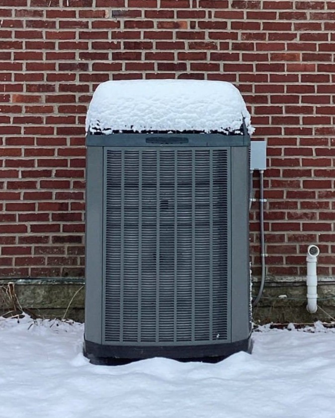 Snow piled on top of Trane AC unit in Dayton, OH, repaired by Logan Services.