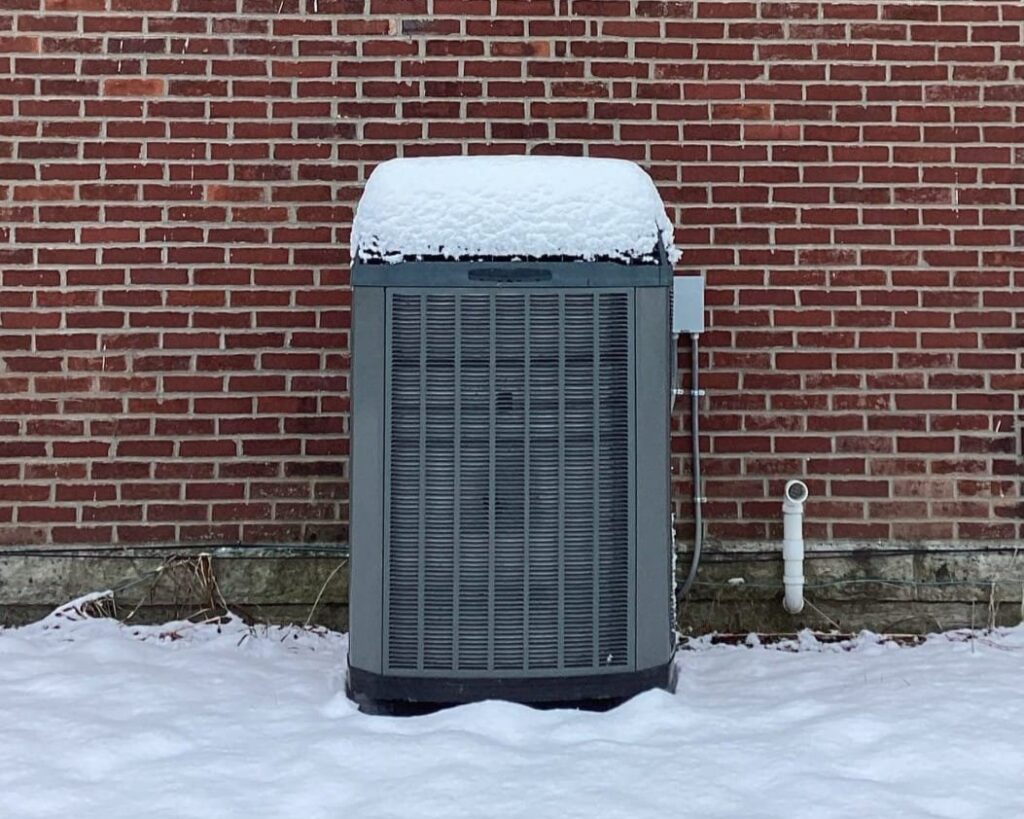 Snow piled on top of Trane AC unit in Dayton, OH, repaired by Logan Services.