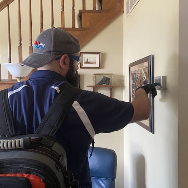 Logan Services HVAC technician adjusting customer's thermostat