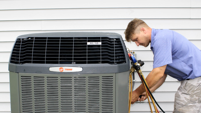 Logan Services technician performing maintenance on a Trane heat pump