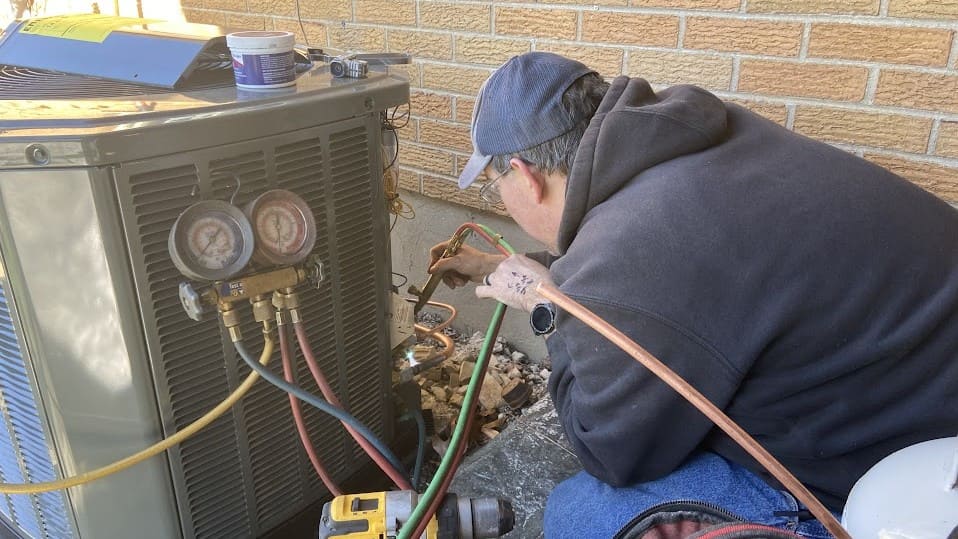 Logan Services HVAC technician brazing gas lines on an AC installation.