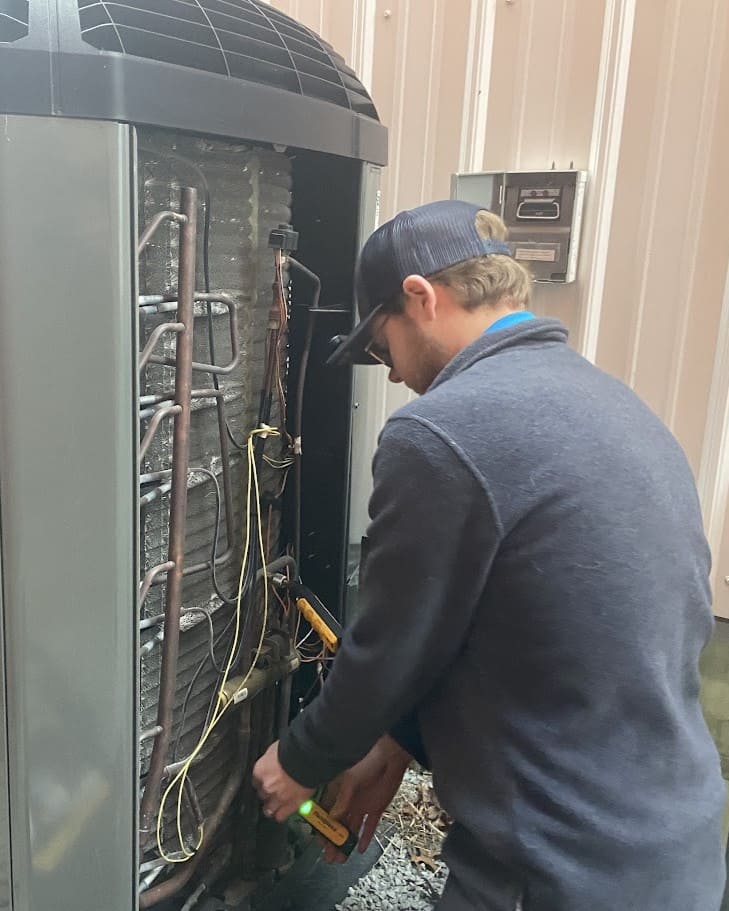 Logan Services HVC technician performing maintenance on Trane AC unit.