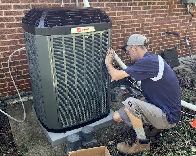 Technician installing a Trane air conditioning unit during residential HVAC installation by Logan Services.