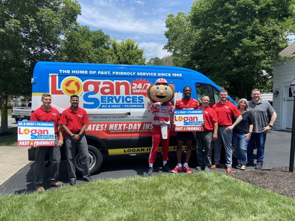 Carnell Tate, Brutus, and Logan Services team posing in front of Logan Services van.