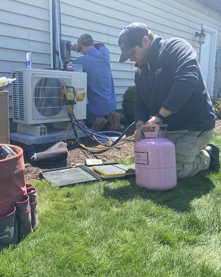Logan Services HVAC technicians installing a Mitsubishi ductless AC unit.