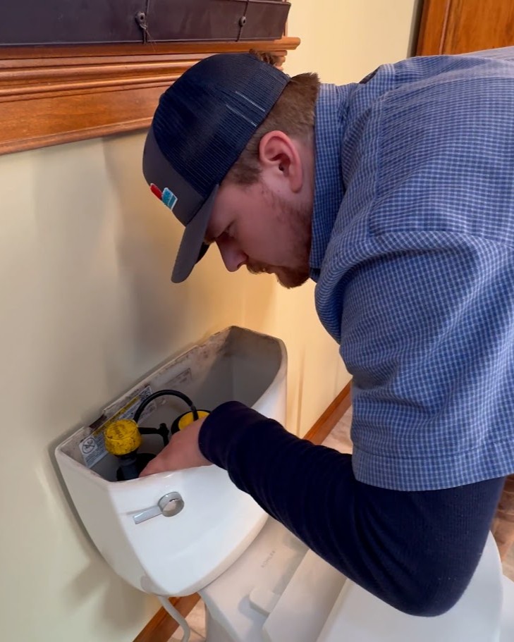 Logan Services plumber inspecting toilet for clogs, drain issues.