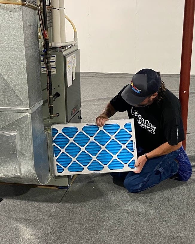 Logan Services HVAC technician replacing a furnace air filter.