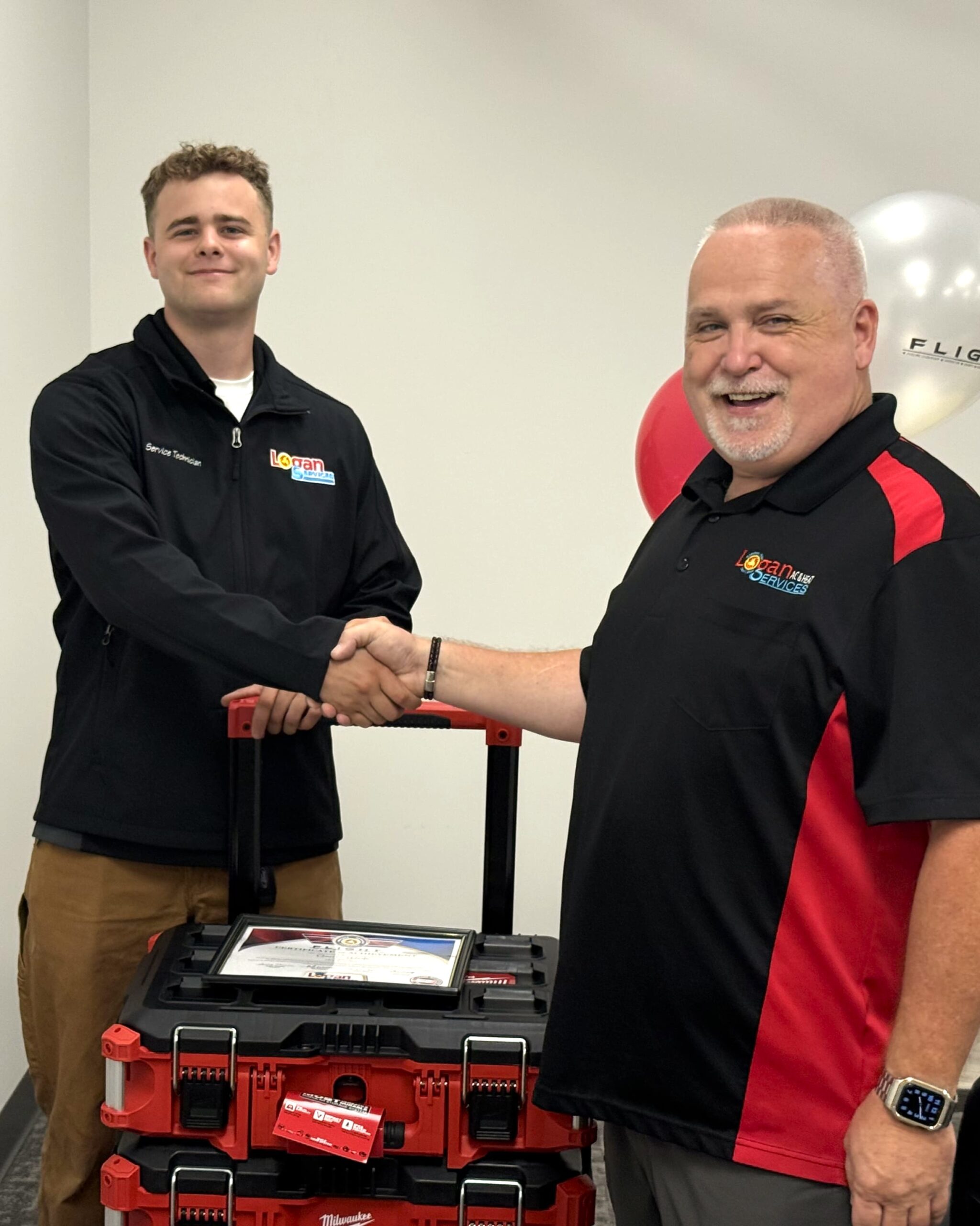 Service Technician Carson, shaking hands with Service Supervisor Bill. Logan Services apprenticeship graduation.