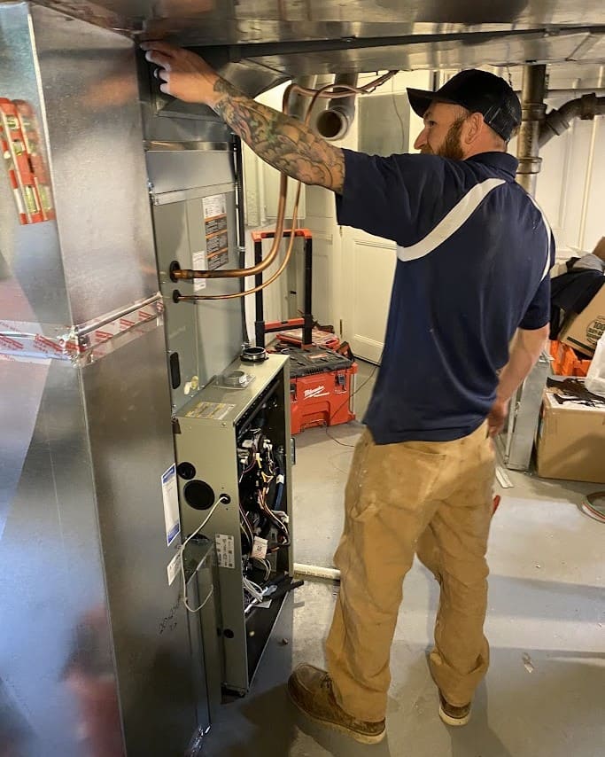 Logan Services HVAC technician performing furnace inspection.