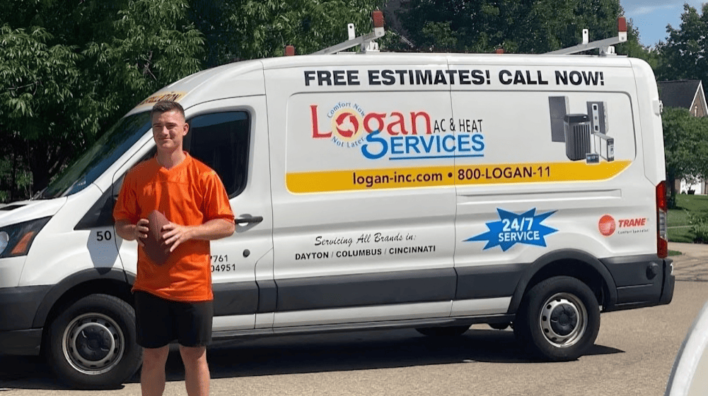 Money Mac posing with football and Logan Services van