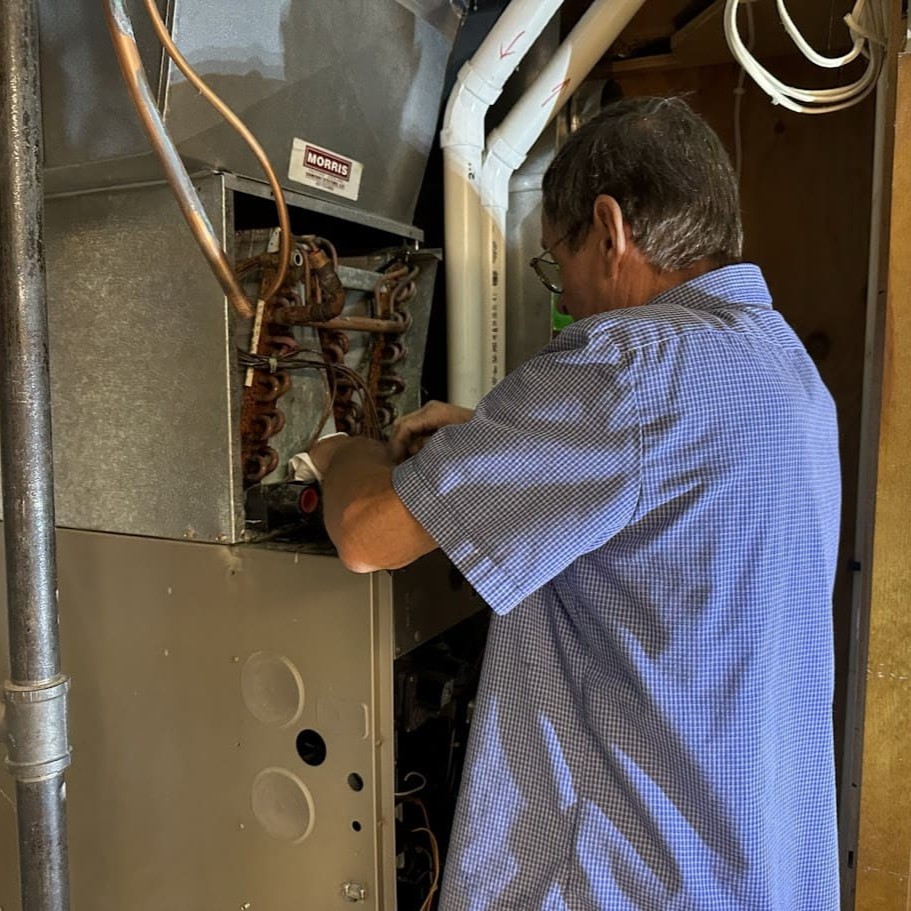 Logan Services HVAC tech repairing furnace coils.