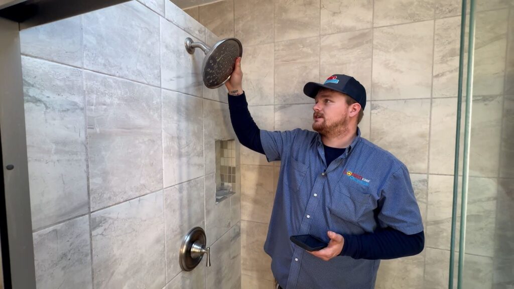 Logan Services plumber inspecting shower head for leaks.