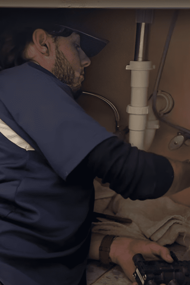 Logan Services plumber inspecting under-sink leak