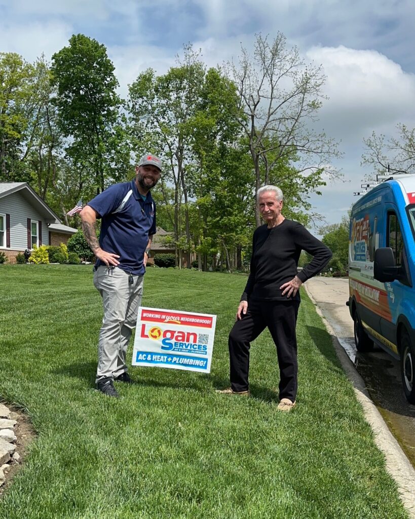 Logan Services HVAC service technician and customer posing with yard sign and LSI van