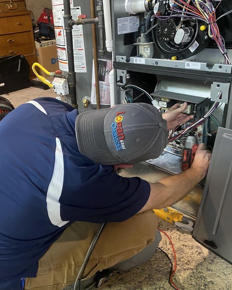 Logan Services HVAC repair technician servicing furnace.