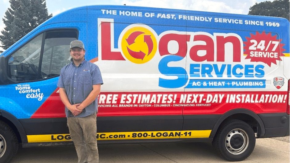 Logan Services plumber posing with branded van.