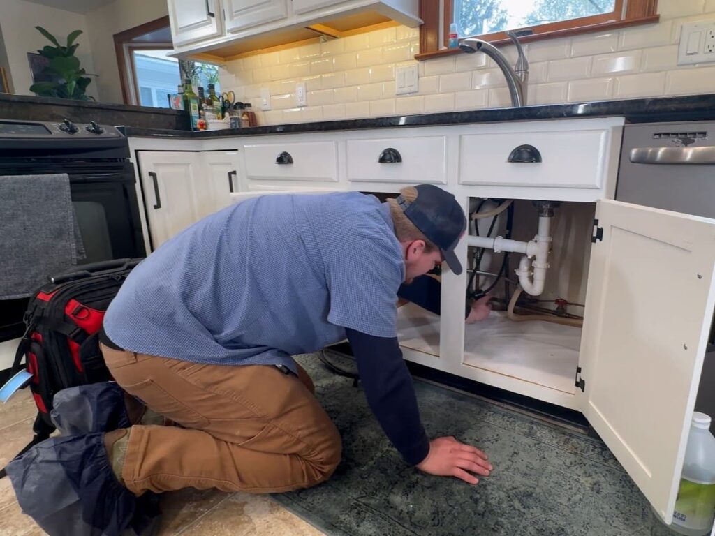 Logan Services plumber inspecting sink pipes