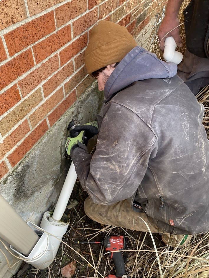 Logan Services plumber repairing sump pump discharge pipe.
