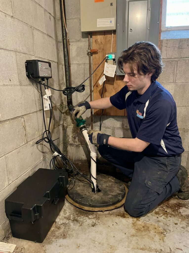 Logan Services plumber inspecting sump pump battery system