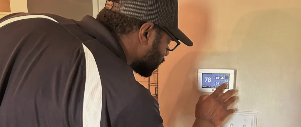 Logan Services HVAC technician adjusting Trane thermostat.