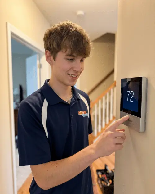 Logan Services HVAC technician adjusting Daikin thermostat