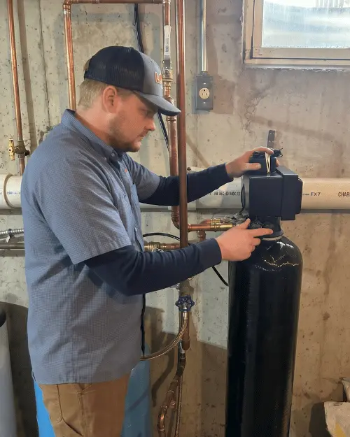 Logan Services plumber installing water filter tank.