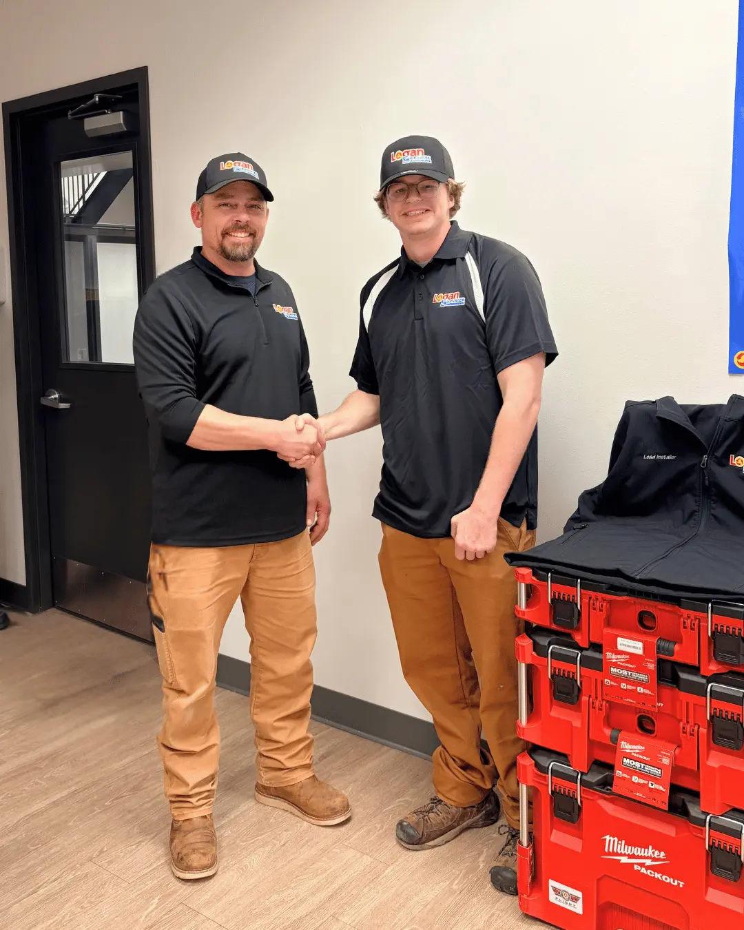 Logan Services install apprenticeship graduate shaking hands with trainer.