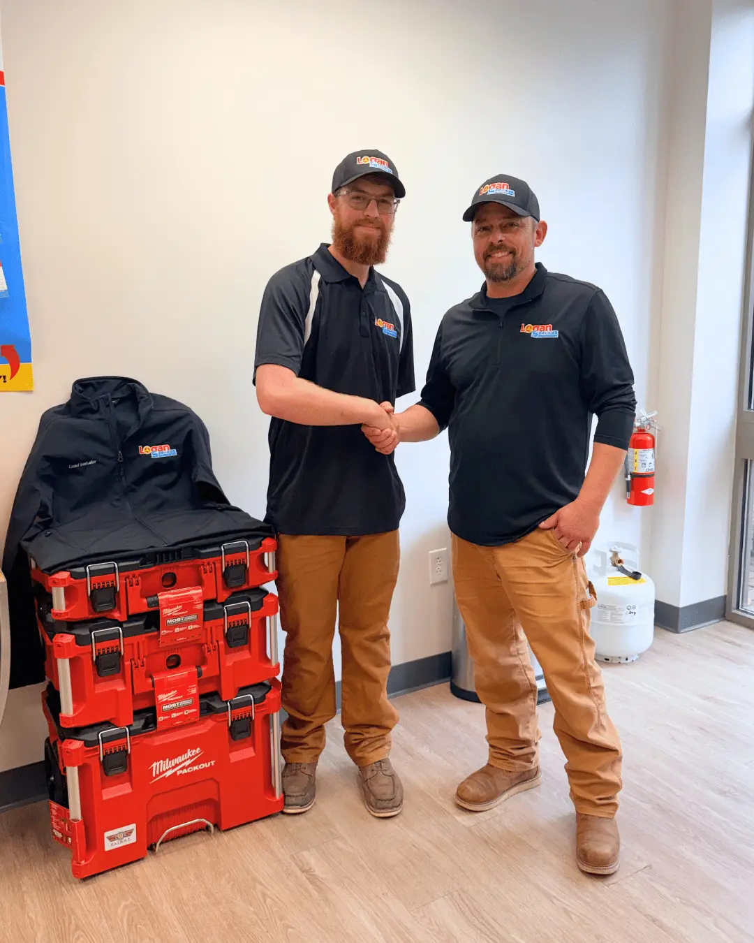 Logan Services install apprenticeship graduate shaking hands with trainer.